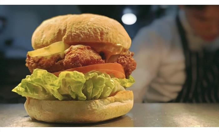 Chicken burger with smoked cheese, burger sauce, gherkins, lettuce, tomatoe, bacon jam with triple cooked chips and slaw